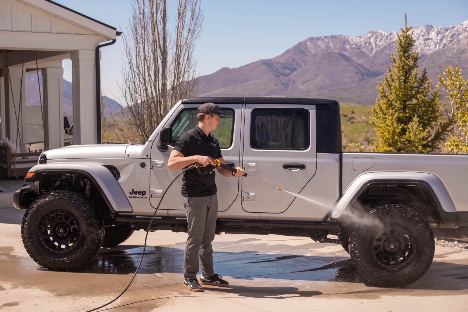 A LivFlo detailer hand-washing a Jeep with the Wasatch mountains in the background.
