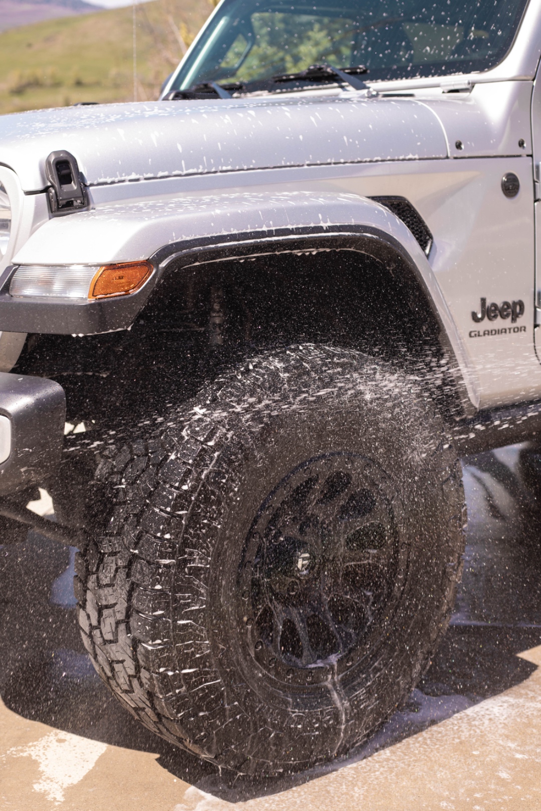 A LivFlo detailer spraying down tires and wheels on a mobile detail.