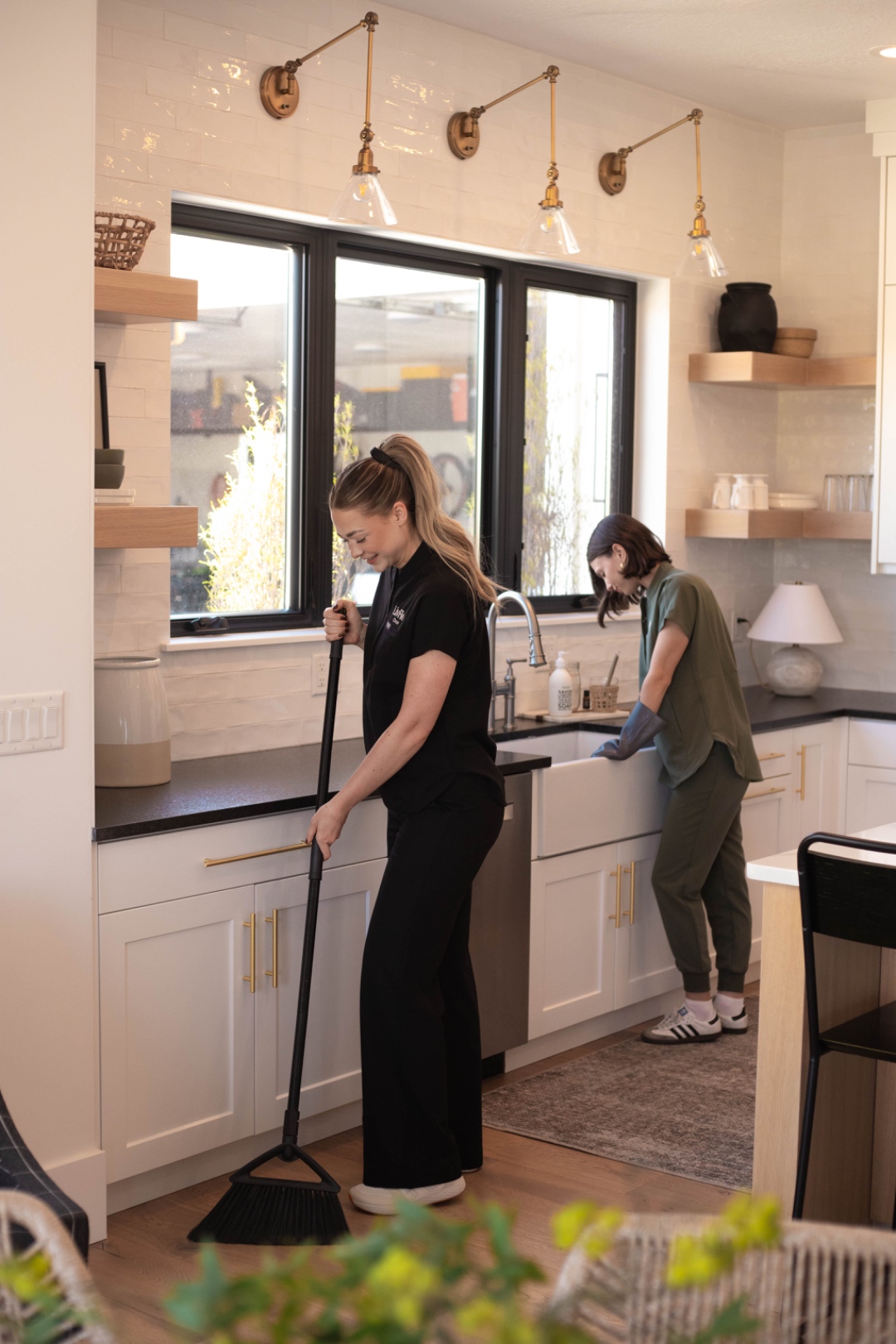 A LivFlo team mopping the floor and finishing the counter in a bright kitchen.