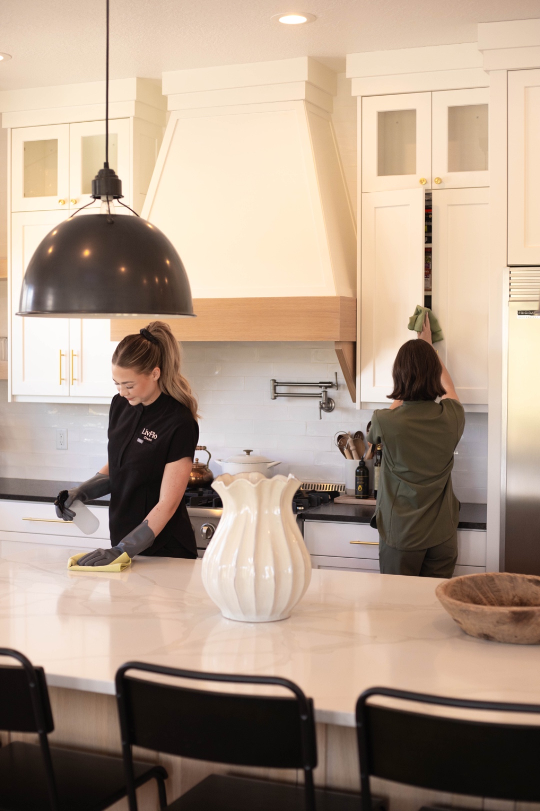 Two LivFlo cleaners working together in a bright kitchen.