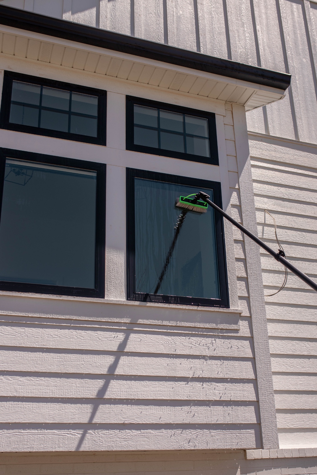 A LivFlo window cleaner using a water-fed pole on a tall window for streak-free results.