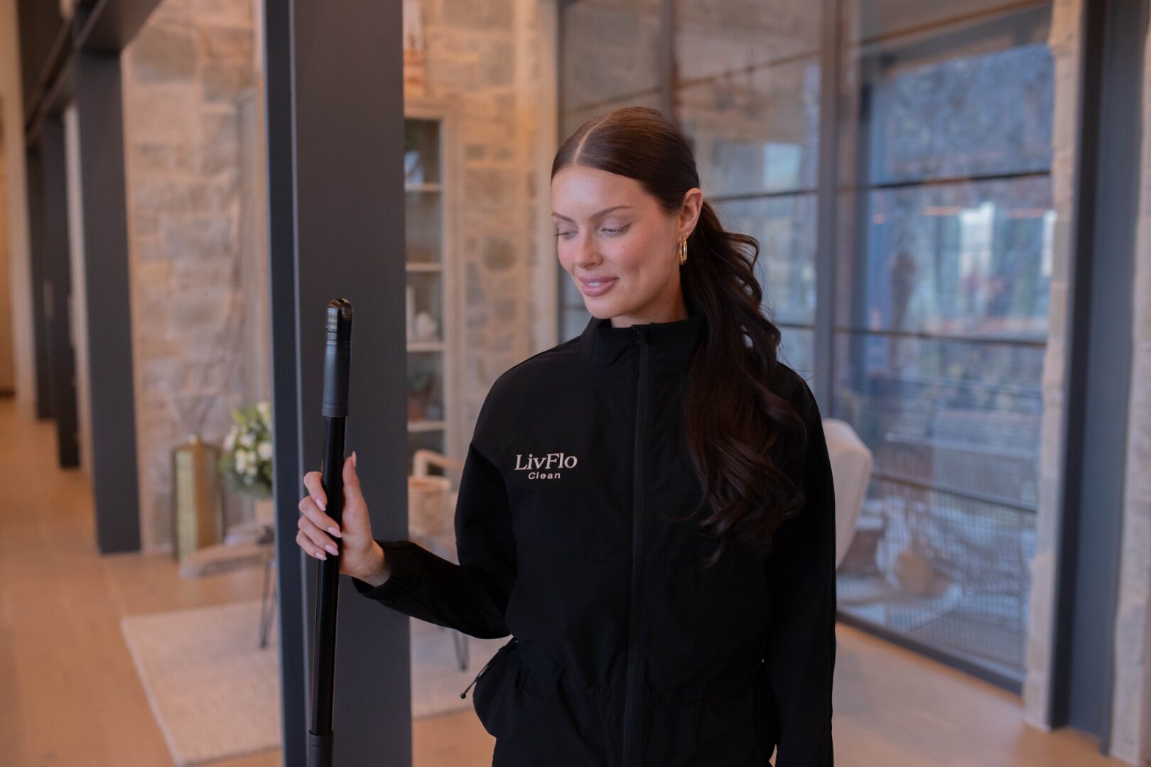 The LivFlo Clean team in branded jackets and sage uniforms inside a modern home with a Wasatch mountain view.