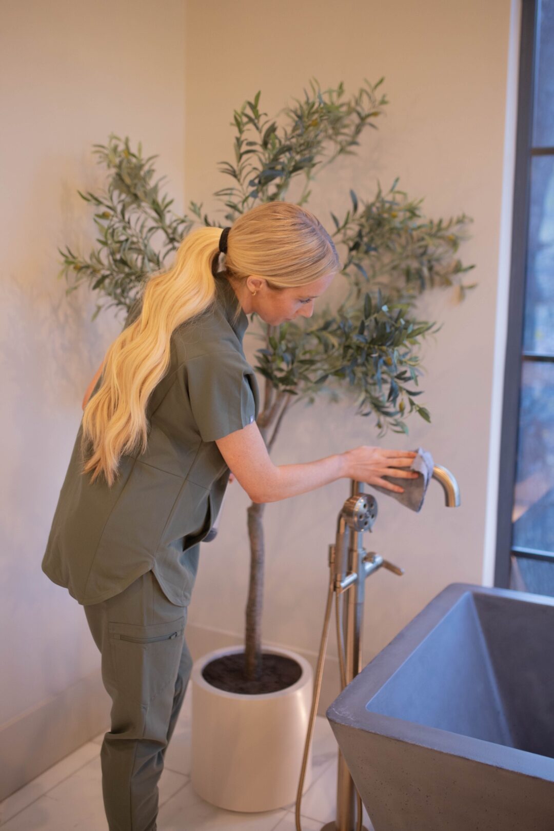 LivFlo's professional dusters and detail brushes neatly arranged on a tufted leather bench beside a modern staircase.